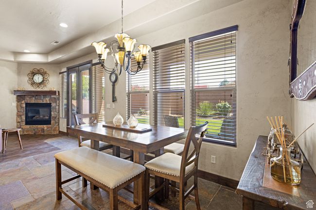 Dining area with stone tile floors, a stone fireplace, a chandelier, a textured wall, and recessed lighting | Image 35