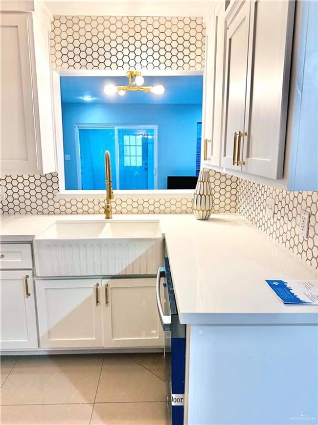 Kitchen with light countertops, light tile patterned floors, tasteful backsplash, and white cabinetry | Image 9