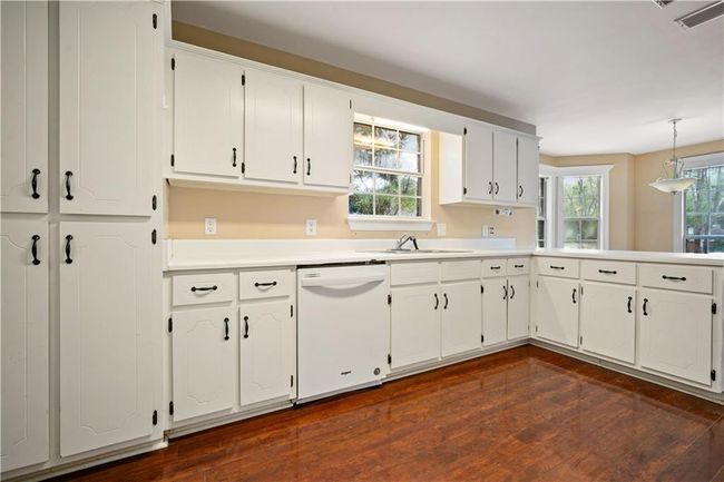 Kitchen with white dishwasher, dark wood-style flooring, and white cabinets | Image 8