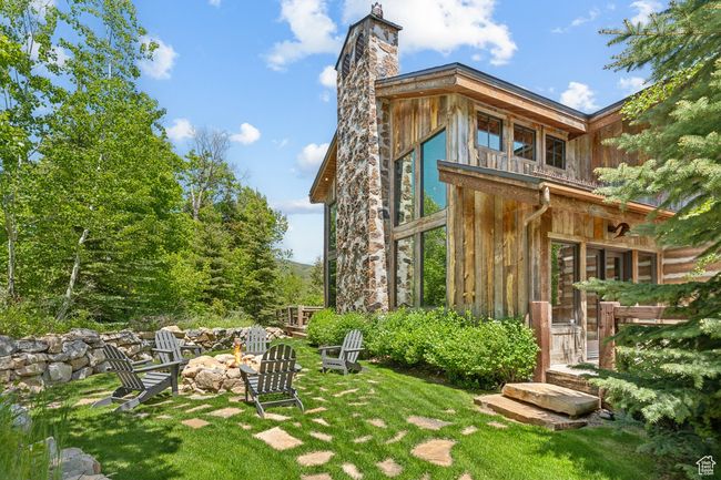 Rear view of house with a fire pit, a chimney, a lawn, and board and batten siding | Image 53