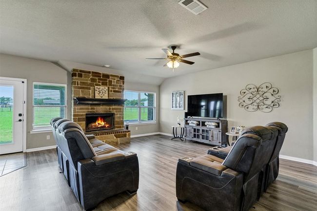 Living room featuring lofted ceiling, a fireplace, ceiling fan, and dark hardwood / wood-style flooring | Image 6