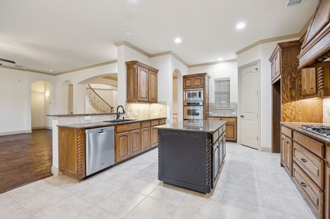 Kitchen with stainless steel appliances, a sink, arched walkways, backsplash, and crown molding | Image 14