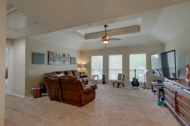 Upstairs living area featuring a ceiling fan, carpet flooring, a raised ceiling, and attic access | Image 21