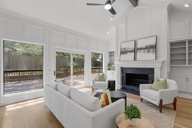 Living room with built in features, a decorative wall, a ceiling fan, light wood-style floors, and a fireplace | Image 5
