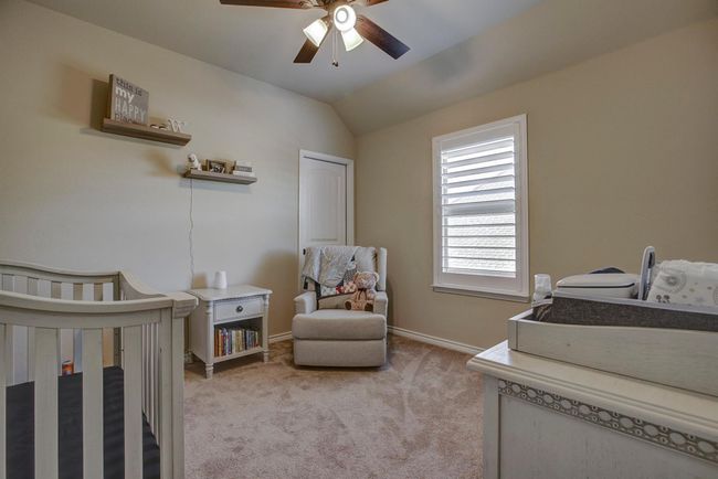 Bedroom featuring a crib, light colored carpet, vaulted ceiling, and ceiling fan | Image 25