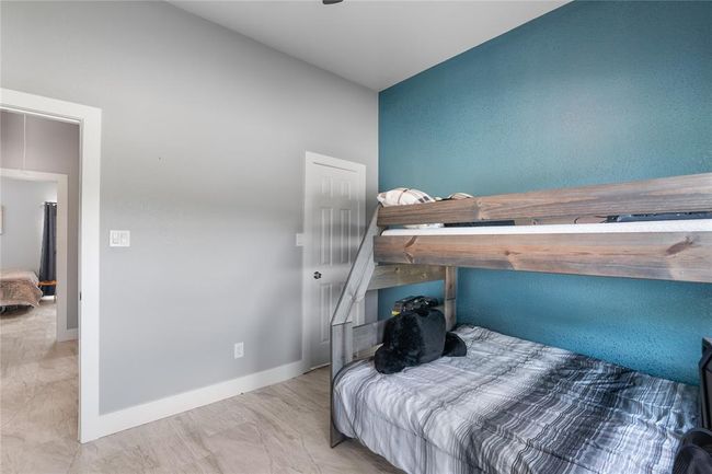Bright and inviting secondary bedroom with stylish accent wall, perfect for guests or a home office. | Image 15