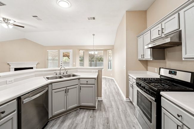 Kitchen featuring appliances with stainless steel finishes, gray cabinets, lofted ceiling, light countertops, and under cabinet range hood | Image 11