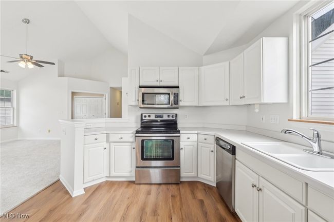 Kitchen featuring white cabinets, stainless steel appliances, a sink, lofted ceiling, and ceiling fan | Image 10