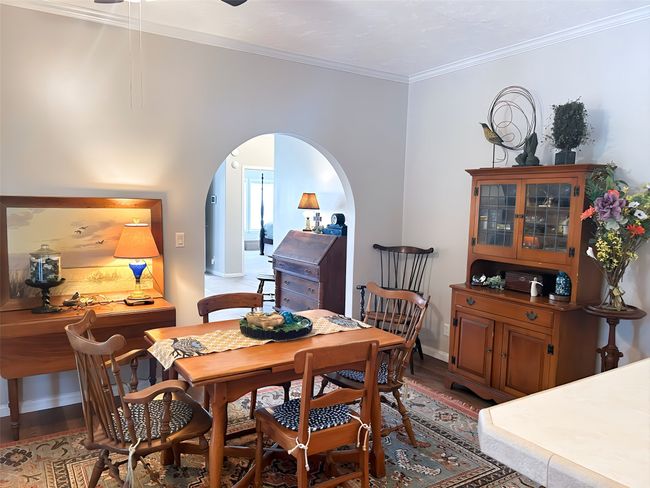 Dining room with baseboards, wood finished floors, crown molding, and arched walkways | Image 4