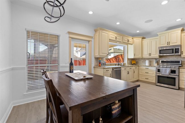 Kitchen with appliances with stainless steel finishes, cream cabinets, backsplash, light wood-style floors, and recessed lighting | Image 5