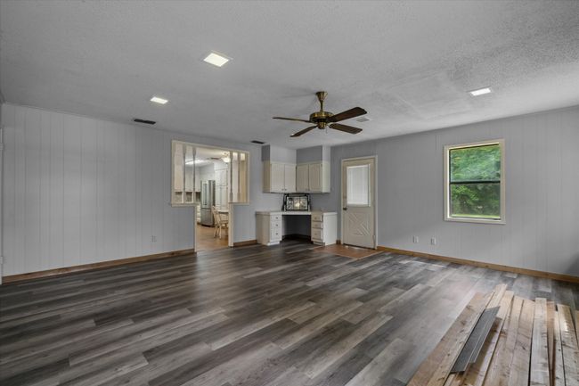 Unfurnished living room with dark wood-style flooring, a ceiling fan, and a textured ceiling | Image 26