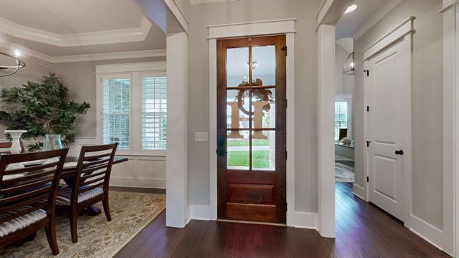Welcome home! This warm and inviting entryway sets the tone with rich hardwood floors, custom trim, and a beautiful wood and glass front door that lets the natural light pour in. | Image 14
