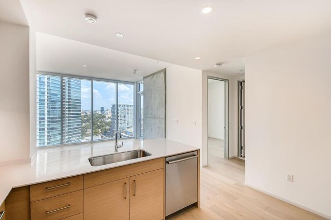 Kitchen featuring stainless steel dishwasher, a sink, light wood-style flooring, light countertops, and recessed lighting | Image 8