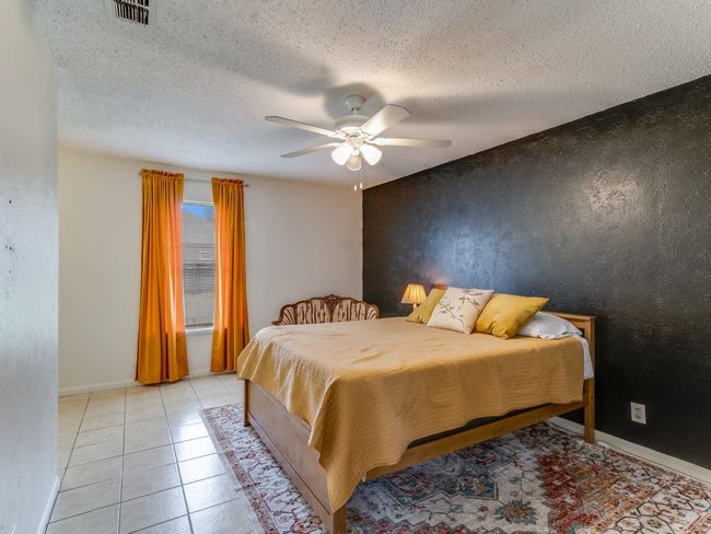 Bedroom with a textured ceiling, ceiling fan, and light tile patterned floors | Image 21