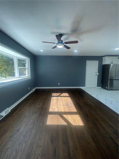 Empty room featuring dark wood-type flooring, ceiling fan, and a textured ceiling | Image 2