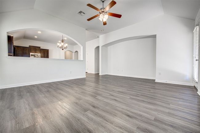 Unfurnished living room featuring lofted ceiling, a ceiling fan, arched walkways, and wood finished floors | Image 21