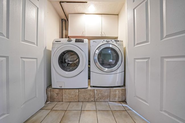 Washroom featuring cabinet space, separate washer and dryer, and light tile patterned floors | Image 26