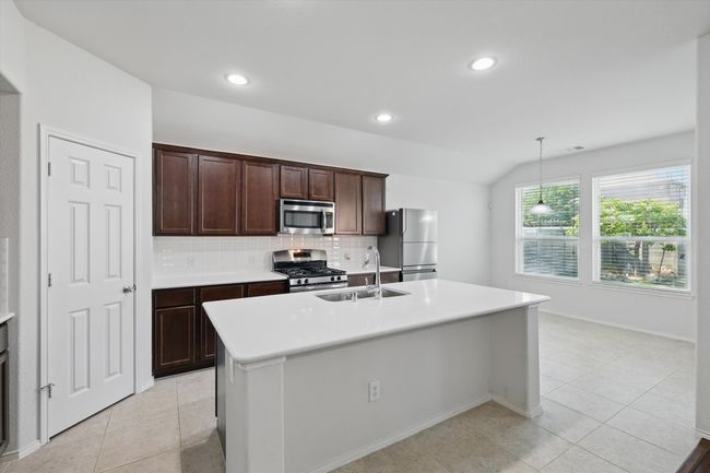 Kitchen featuring tasteful backsplash, a sink, light tile patterned floors, stainless steel appliances, and light countertops | Image 22