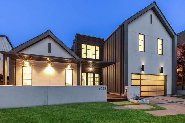 Rear view of house with board and batten siding, an attached garage, a yard, and driveway | Image 36