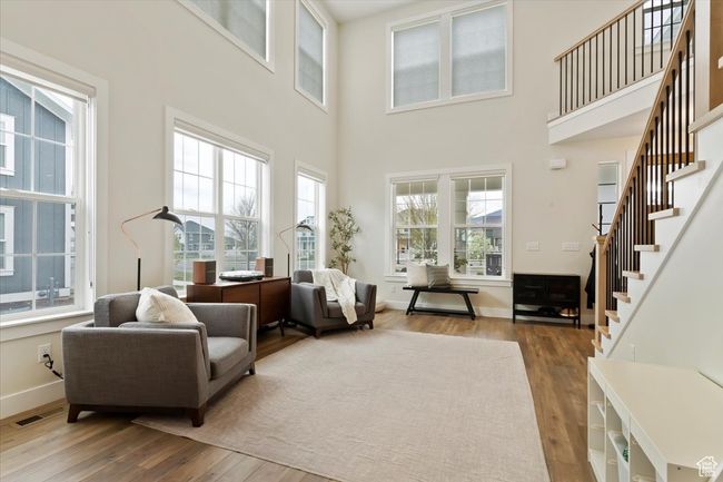 Living room with baseboards, a high ceiling, hardwood / wood-style flooring, and stairs | Image 6