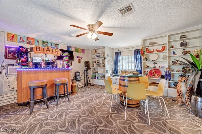 Carpeted dining room featuring a ceiling fan, a textured ceiling, and a bar | Image 17