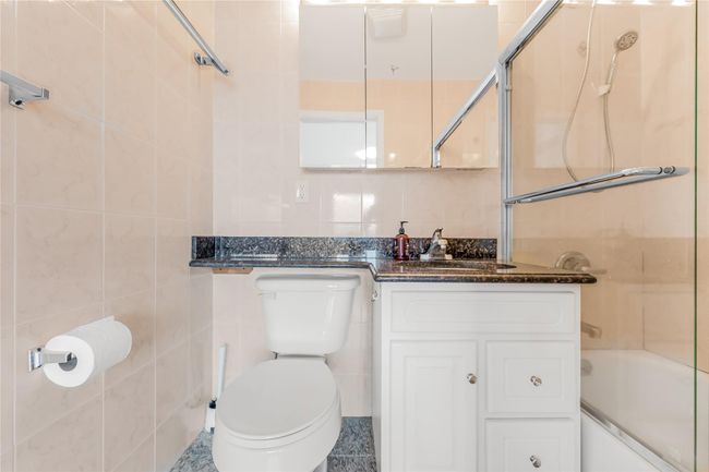 Bathroom with tile walls, combined bath / shower with glass door, and vanity | Image 23