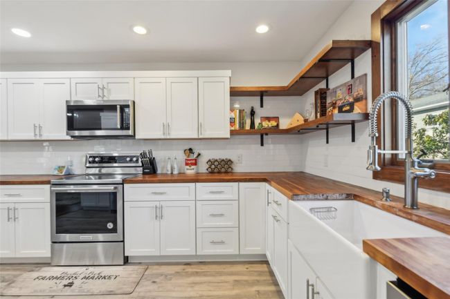 Kitchen with a sink, butcher block countertops, appliances with stainless steel finishes, white cabinetry, and backsplash | Image 17