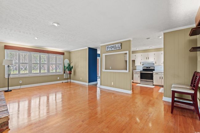 Unfurnished living room featuring light wood-style flooring, a textured ceiling, crown molding, and baseboards | Image 4