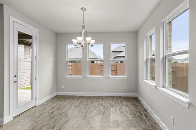 Unfurnished dining area with a chandelier, light wood finished floors, and baseboards | Image 8