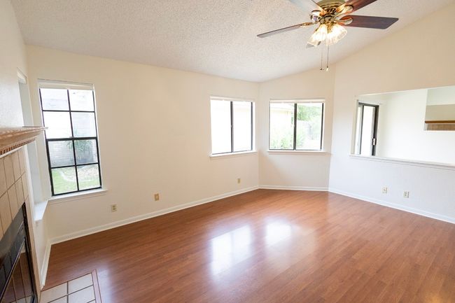 Unfurnished living room with ceiling fan, wood finished floors, a tile fireplace, healthy amount of natural light, and vaulted ceiling | Image 11