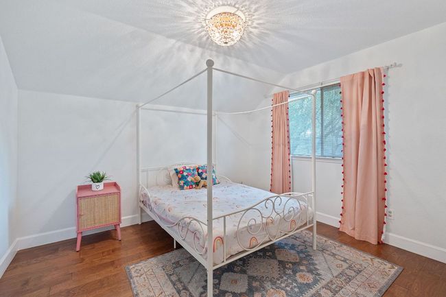 Bedroom with vaulted ceiling, wood finished floors, and a chandelier | Image 26