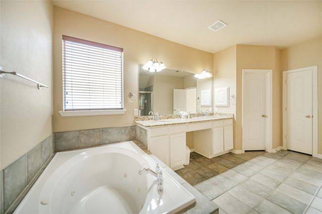 Bathroom featuring double vanity, a tub with jets, and a stall shower | Image 23
