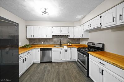 Kitchen featuring white cabinets, dark wood-type flooring, appliances with stainless steel finishes, and sink | Image 2