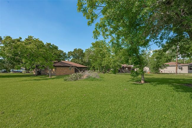 Spacious back yard with lush grass and mature shade trees. Plenty of room for outdoor games/play, landscaping, or a garden | Image 27