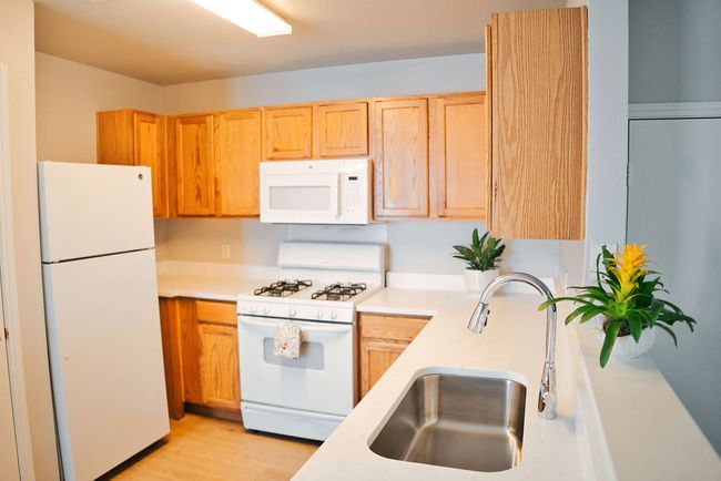 Kitchen with white appliances, light countertops, light wood-style flooring, and light brown cabinetry | Image 10