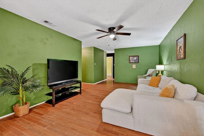 Living area with ceiling fan, wood finished floors, and a textured ceiling | Image 6