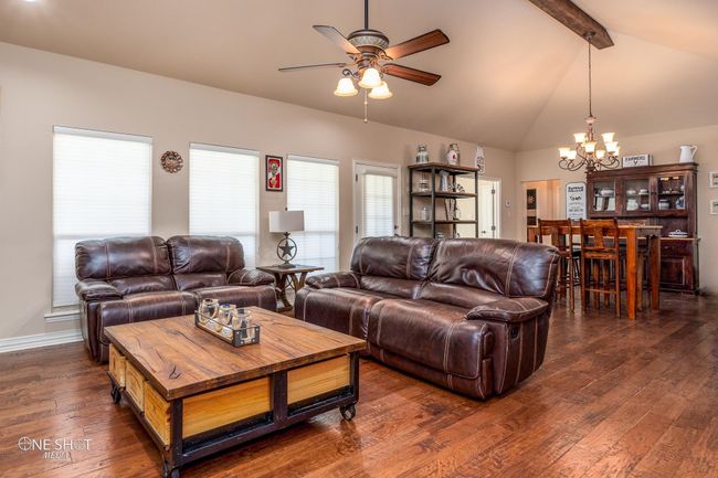Living area with a chandelier, ceiling fan, beam ceiling, dark wood finished floors, and baseboards | Image 10
