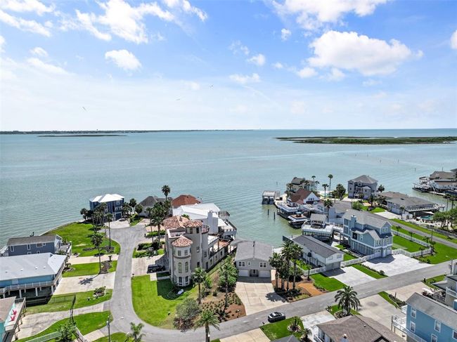 This photo showcases a Tiki Island's picturesque views of a tranquil bay. The area features spacious homes, palm trees, and boat docks, offering a serene coastal lifestyle. | Image 32