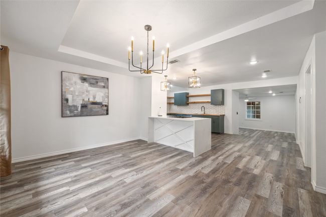 Kitchen featuring open shelves, a chandelier, dark wood-style flooring, a sink, and a peninsula | Image 6
