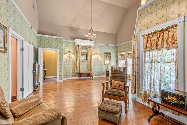 Living area featuring a notable chandelier, wallpapered walls, vaulted ceiling, and hardwood / wood-style flooring | Image 27