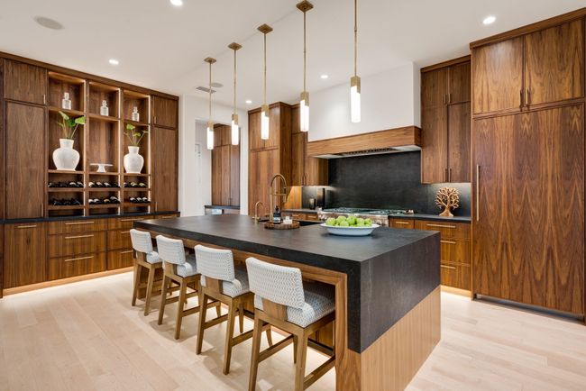 Kitchen featuring dark countertops, backsplash, a kitchen bar, light wood-style flooring, and open shelves | Image 7