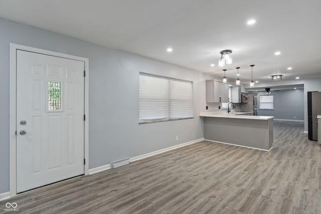 kitchen featuring baseboards, light countertops, a peninsula, recessed lighting, and wood finished floors | Image 9