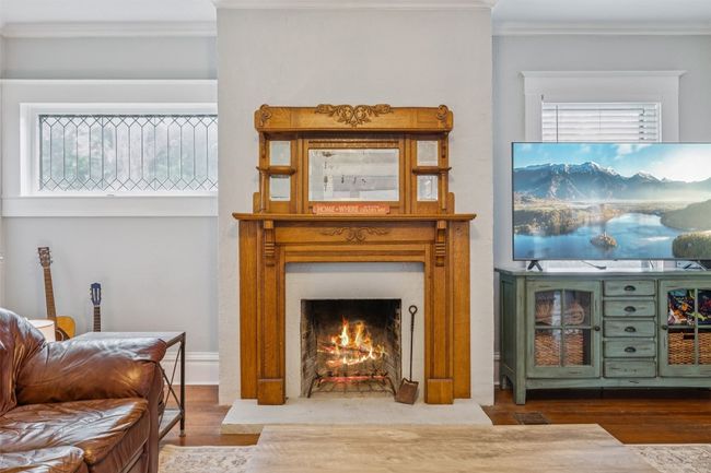 Living room with ornamental molding, wood finished floors, and a warm lit fireplace | Image 7