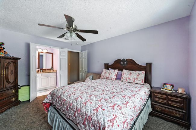 Bedroom featuring carpet flooring, a textured ceiling, ceiling fan, and ensuite bathroom | Image 14