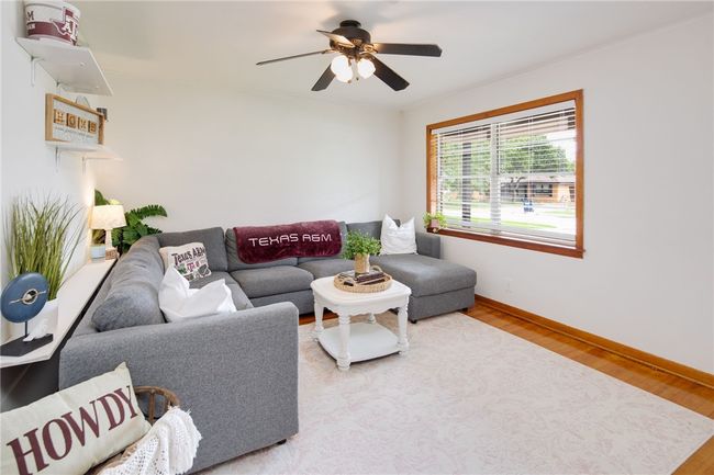 Living room with wood finished floors, a ceiling fan, and baseboards | Image 4