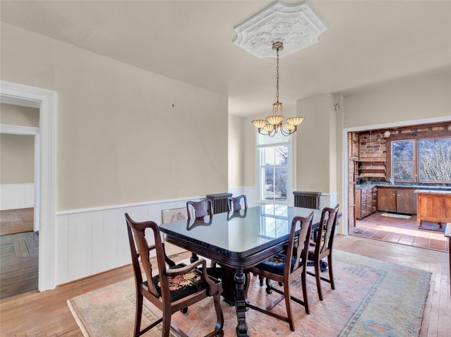Dining space with light wood finished floors, an inviting chandelier, and wainscoting | Image 10