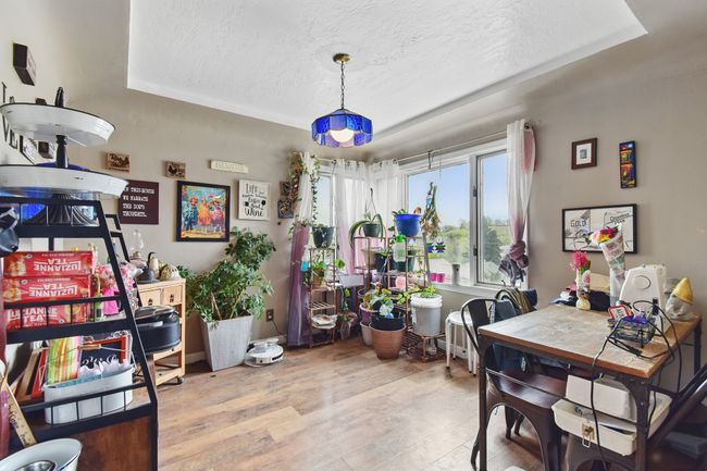 Dining room featuring a textured ceiling, light wood-style flooring, and a tray ceiling | Image 14