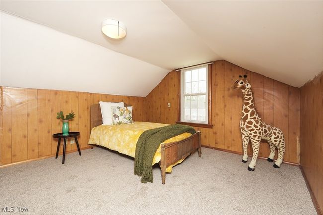 Carpeted bedroom with vaulted ceiling and wooden walls | Image 29