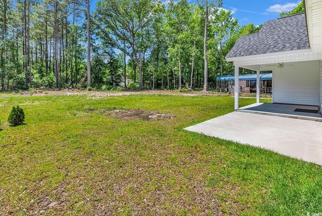 View of green lawn featuring a ceiling fan and an attached carport | Image 35