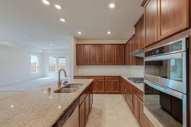 Kitchen featuring appliances with stainless steel finishes, a sink, light stone counters, backsplash, and recessed lighting | Image 10